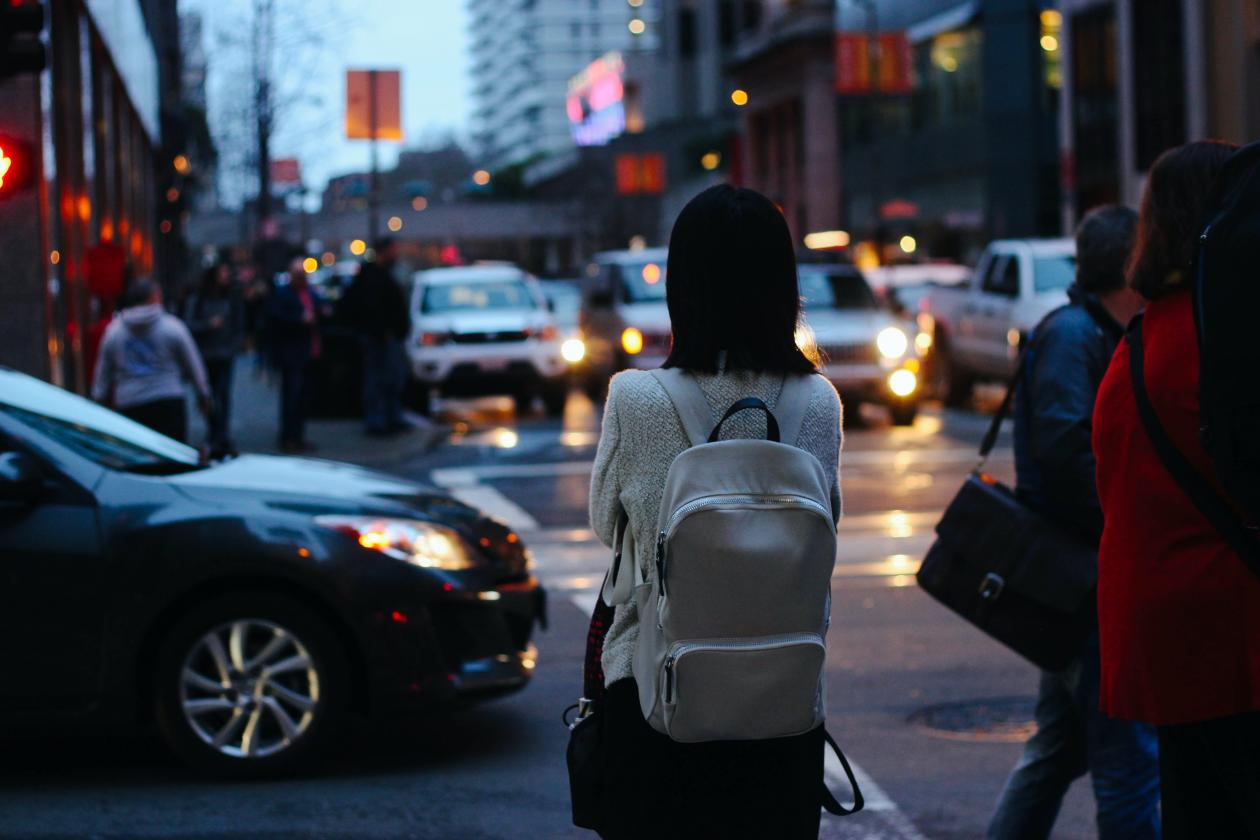 Woman standing at a busy street intersection.
